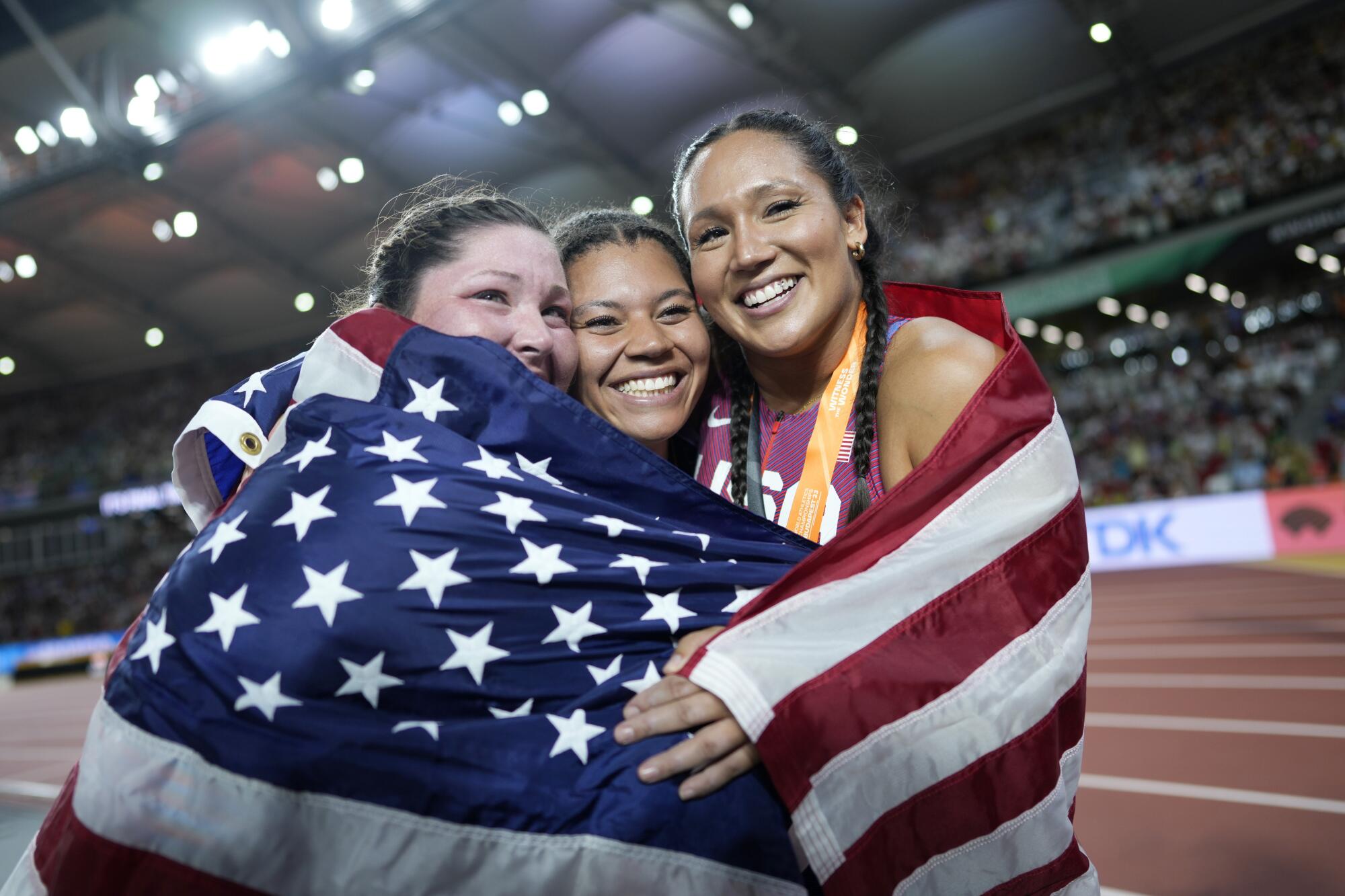 Americans Deanna Price, left, and Janee' Kassanavoid flank Camryn Rogers of Canada after winning medals in the hammer throw.
