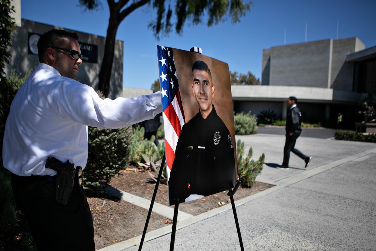 A man sets up a portrait of a police officer on an easel