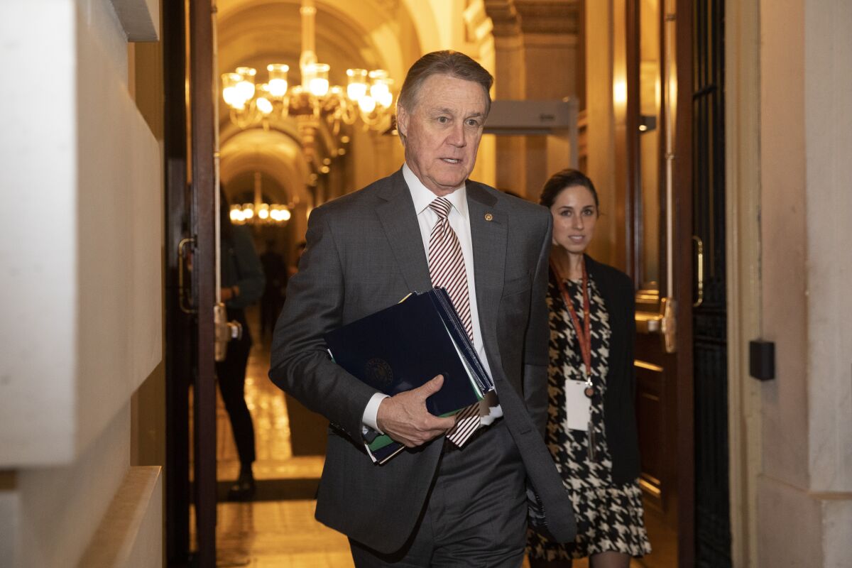 FILE - In this Jan. 31, 2020, file photo, Sen. David Perdue, R-Ga., leaves Capitol Hill in Washington. Perdue has taken down a digital campaign ad featuring a manipulated picture of his Demoncratic opponent, Jon Ossoff, who is Jewish, with an enlarged nose. A spokeswoman for Perdue said in a statement Monday, July 27, 2020, that the image has been removed from Facebook, calling it an “unintentional error” by an outside vendor, without naming the vendor. (AP Photo/Jacquelyn Martin, File)