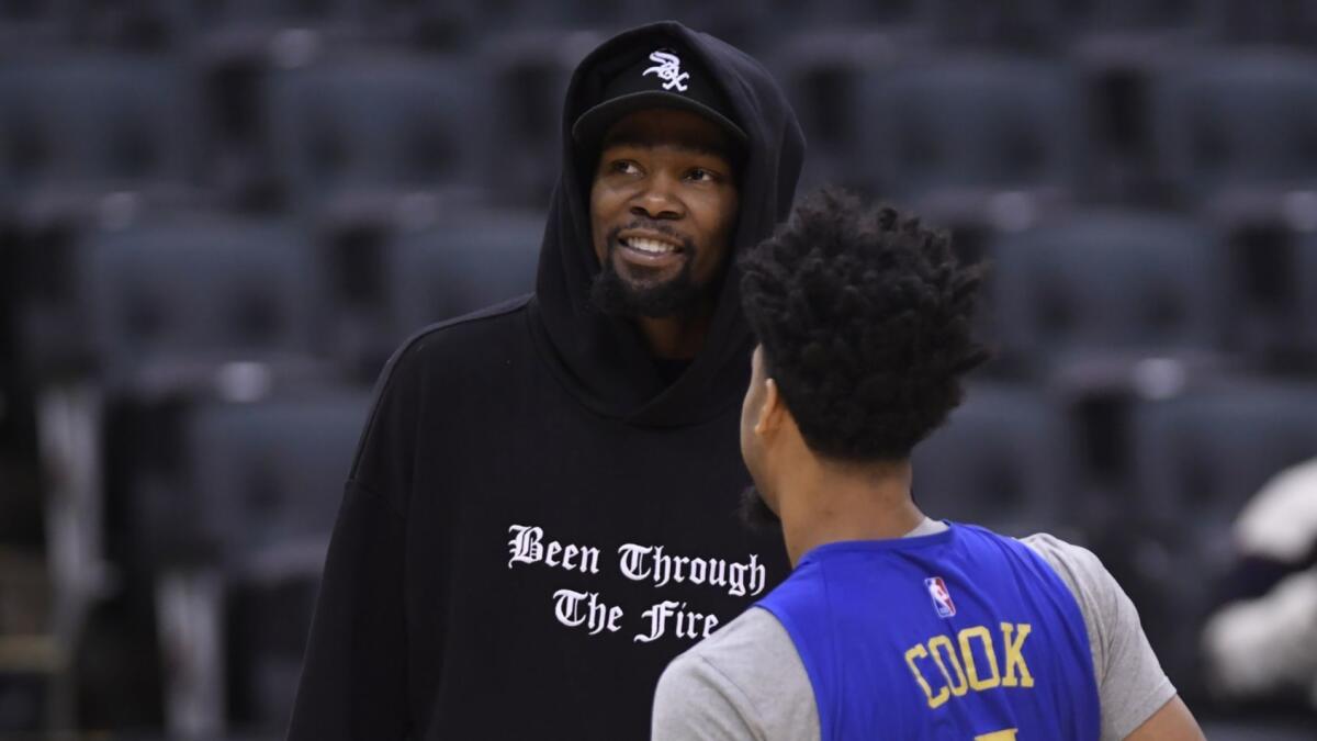 Golden State Warriors forward Kevin Durant, left, speaks with teammate Quinn Cook during practice on June 1.
