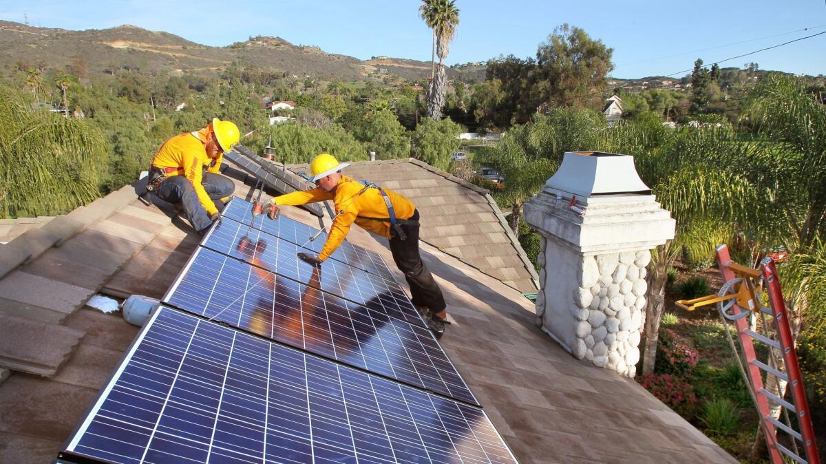 Workers from Sullivan Solar Power install panels on the roof of a home in Vista. At left is Cory Hurley and at right is Eric Hartley.