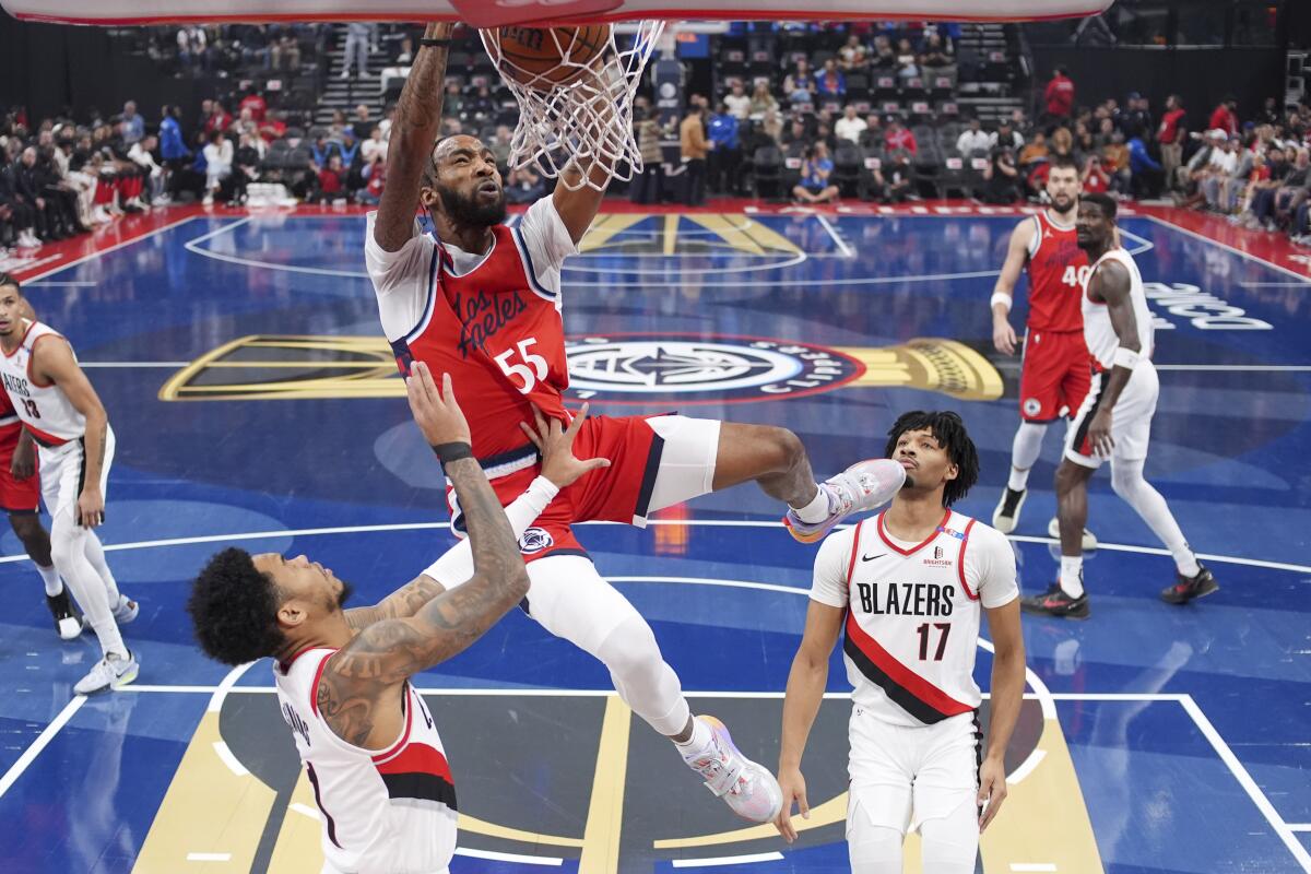 Clippers forveti Derrick Jones Jr. (ortada), Trail Blazers guardları Anfernee Simons (solda) ve Shaedon Sharpe'ın üzerinden smaç basıyor.
