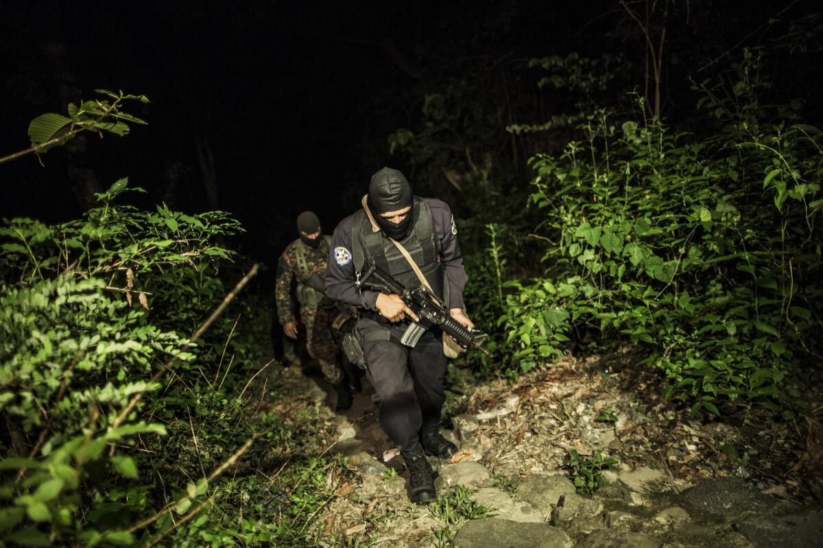 En esta imagen del 27 de mayo de 2015, un agente de policía y un soldado patrullan una zona rural tras violentos enfrentamientos entre policía y pandilleros.