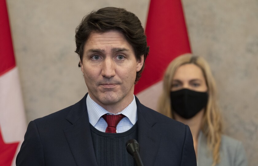 Canadian Prime Minister Justin Trudeau announces Canada will join a diplomatic boycott of the Beijing Winter Olympics over human rights concerns in Ottawa, Ontario, Wednesday, Dec. 8, 2021. Looking on at rear is Sport Minister Pascale St-Onge. (Adrian Wyld/The Canadian Press via AP)