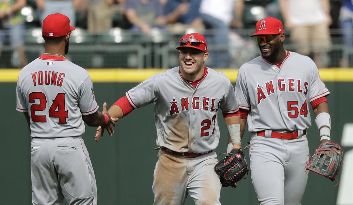 Los Angeles Angels outfielders Chris Young, left, Mike Trout, center, and Jabari Blash, right, greet each other at the end of a baseball game against the Seattle Mariners, Sunday, May 6, 2018, in Seattle.