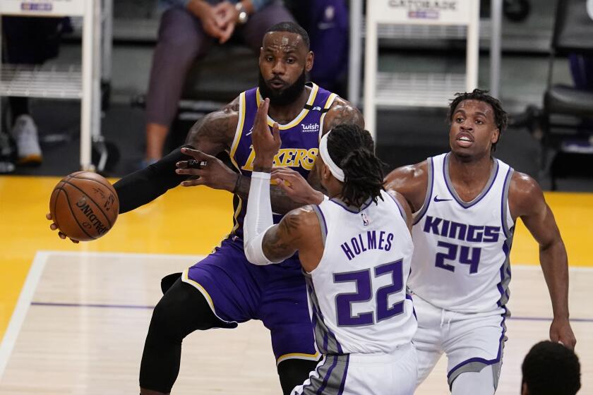 Los Angeles Lakers forward LeBron James, left, passes the ball past Sacramento Kings center Richaun Holmes.