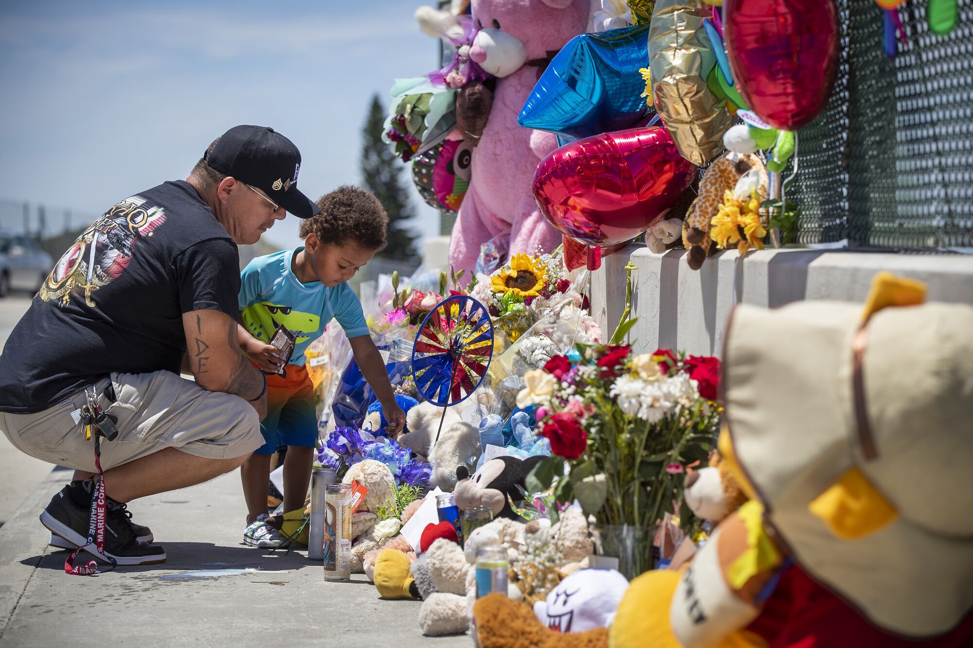 Albert Lamonte of Huntington Beach helps his son, Marcel, 2, place flowers and a pinwheel at a memorial for Aiden Leos.