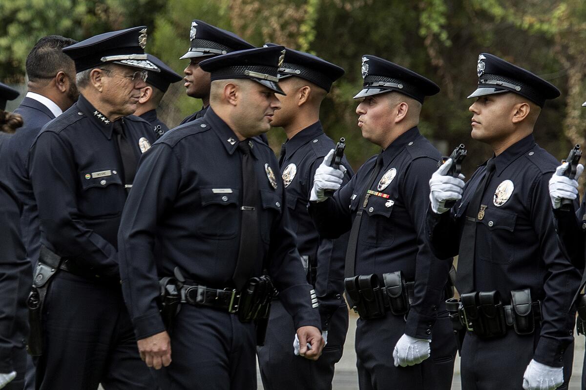 Chief Michel Moore, left, and LAPD Capt. Christopher Zine, to his immediate right, conduct a uniform inspection.