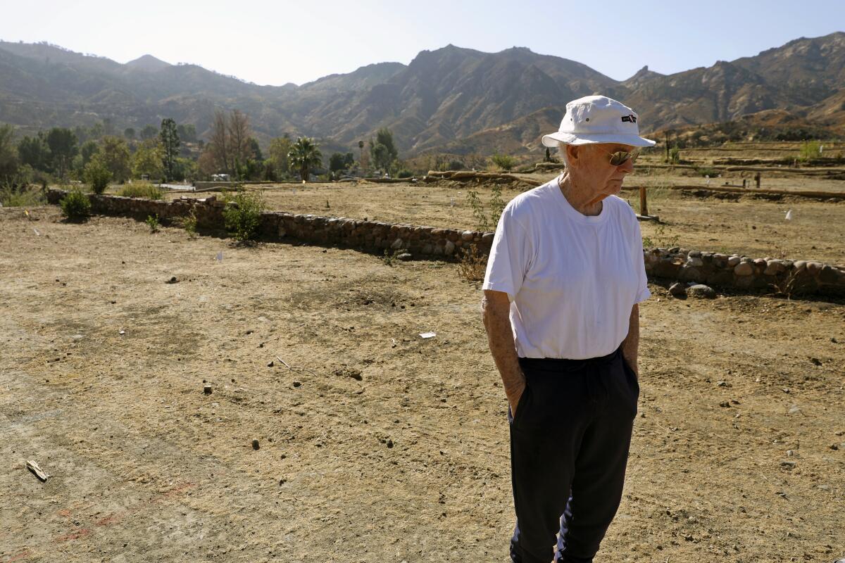 A man stands on a vacant lot where his mobile home once stood.