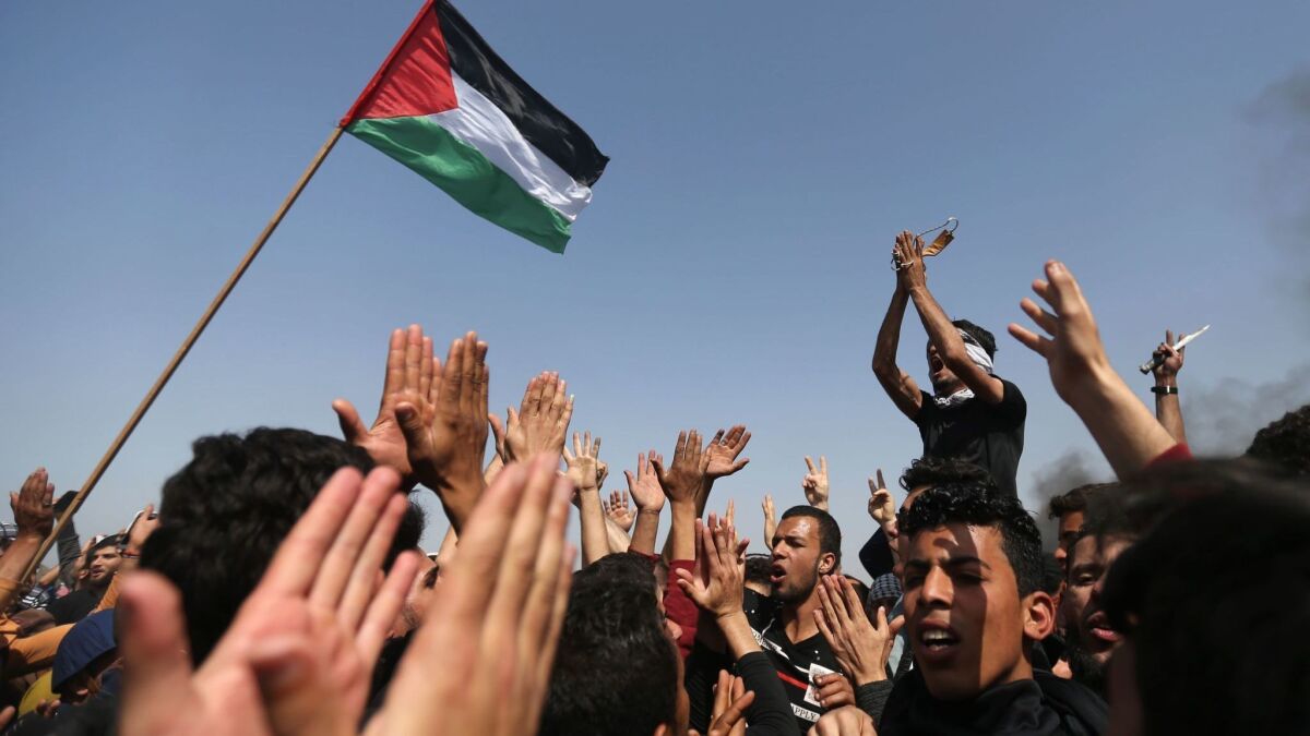 Palestinian demonstrators wave their national flag and shouts slogans against the Israeli security forces during a protest on the Israel-Gaza border on April 6.