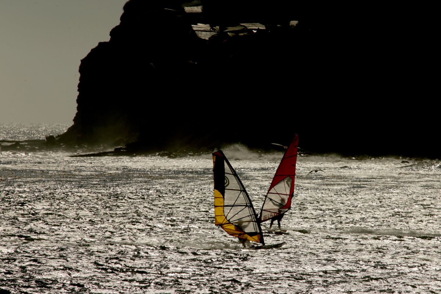 A cool breeze propels windsurfers across the shimmering waters off Cabrillo Beach in San Pedro.