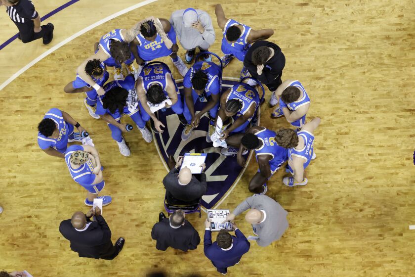 UCLA players surround head coach Mick Cronin during a timeout as seen from above against Washington during the second half of an NCAA college basketball game, Sunday, Jan. 1, 2023, in Seattle. UCLA won 74-49. (AP Photo/John Froschauer)