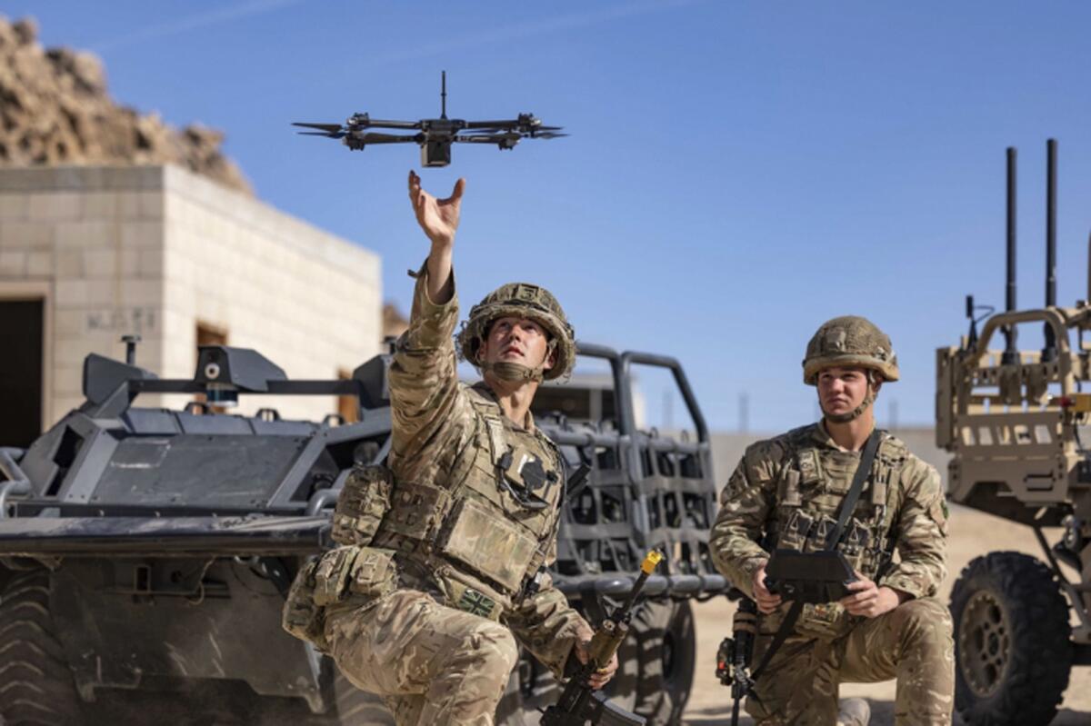 Soldiers in camouflage launch a drone. 