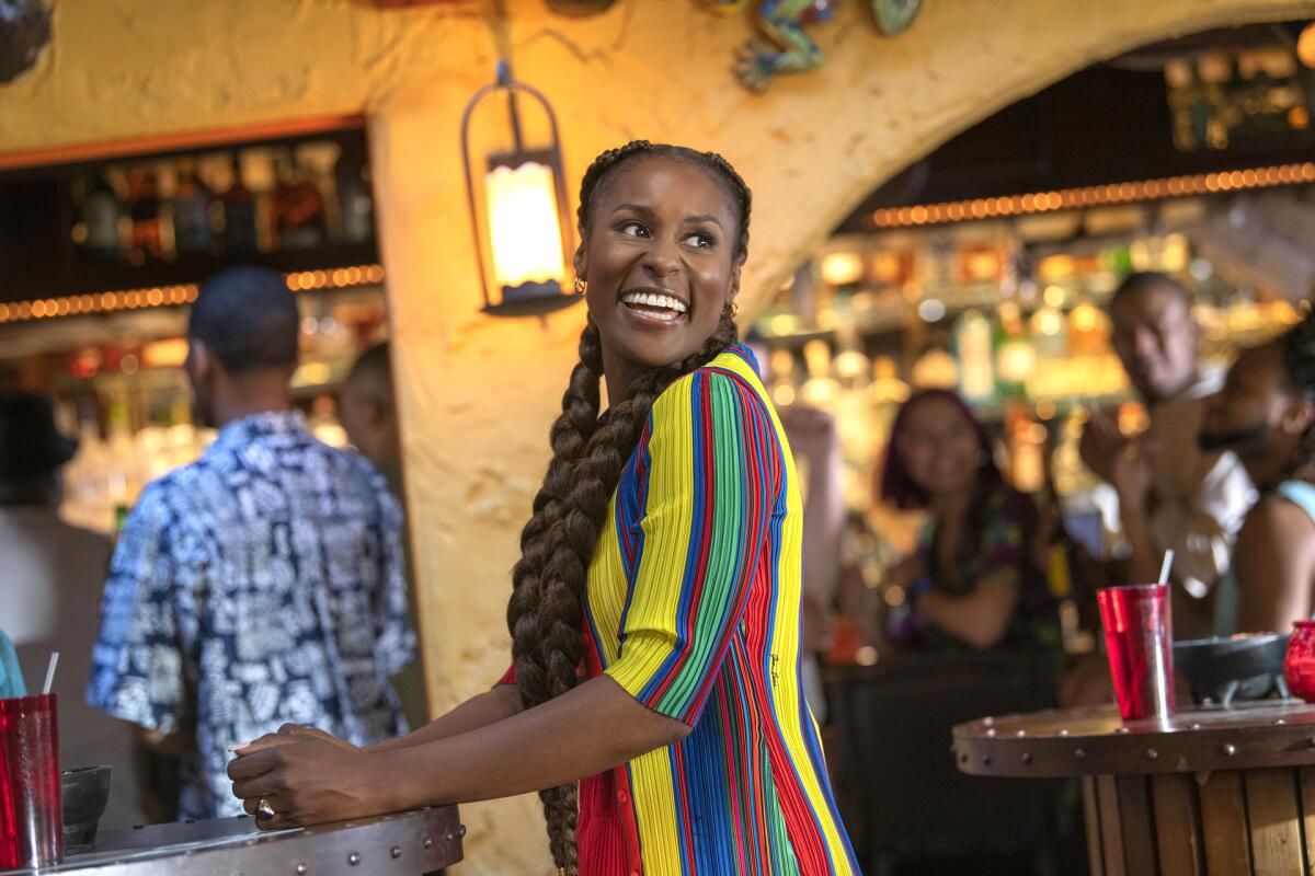 A woman stands in a restaurant with people in the background.