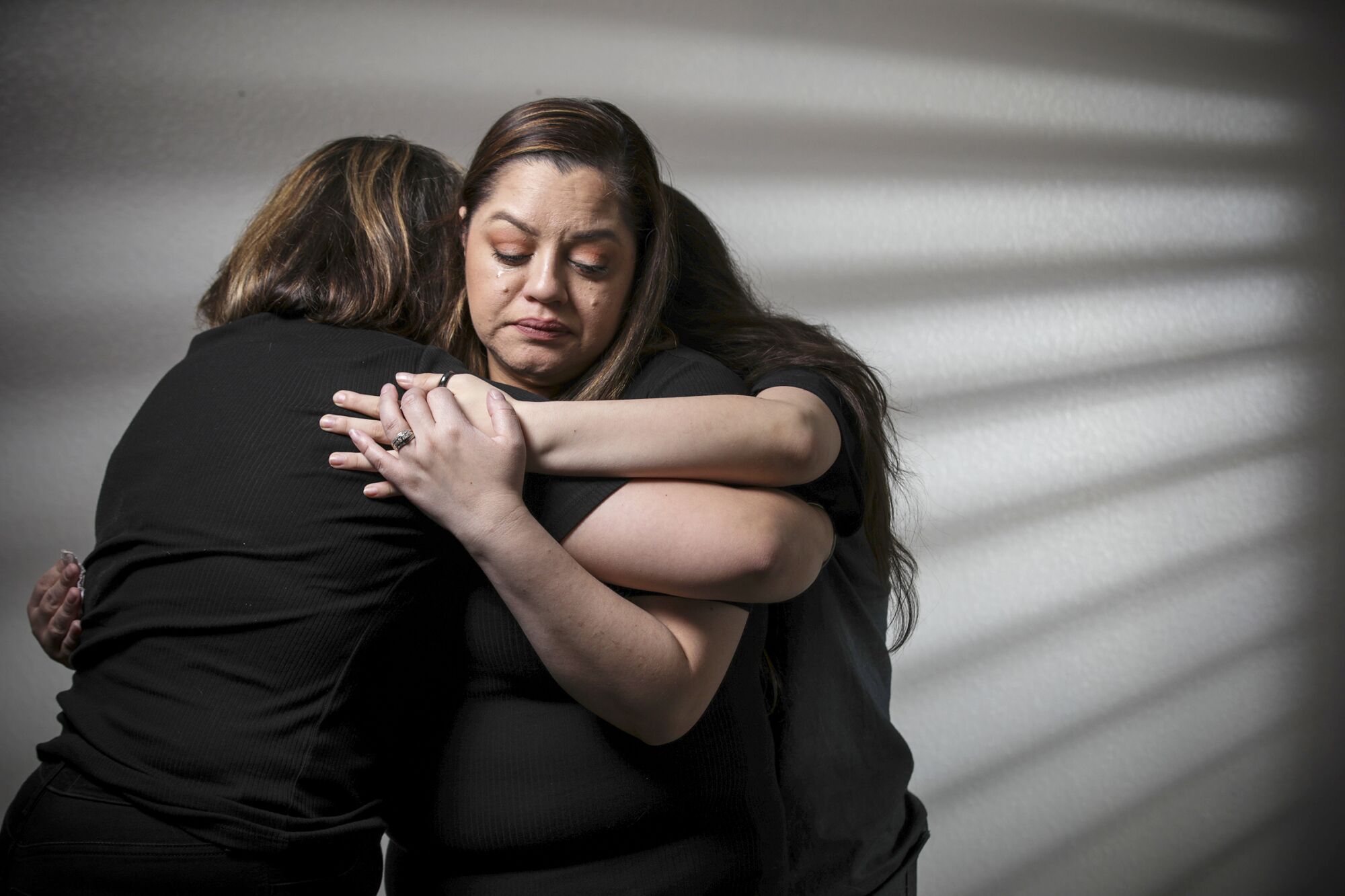 Stephanie Reyes is comforted by her two daughters Marissa Reyes, left, and Reyna Reyes, at their home in Menifee.