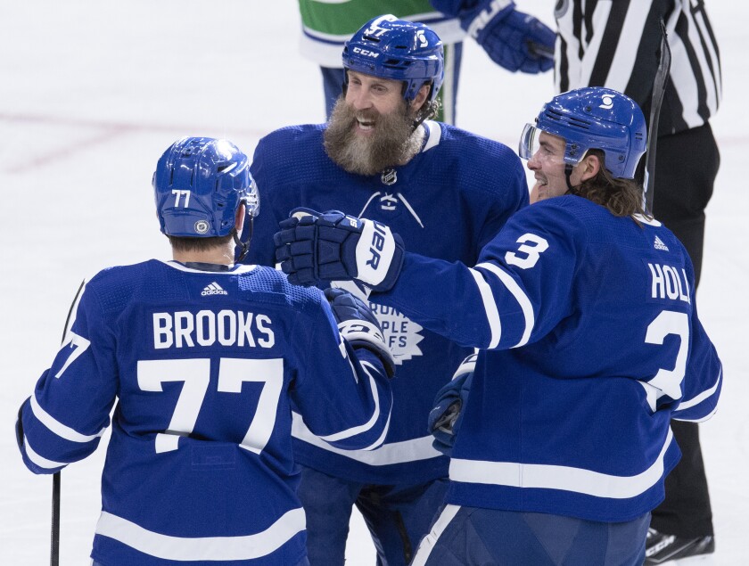 Toronto Maple Leafs centre Joe Thornton (97) and defenseman Justin Holl (3) congratulate center Adam Brooks (77) after his goal against the Vancouver Canucks during third-period NHL hockey game action in Toronto on Saturday, May 1, 2021. (Frank Gunn/The Canadian Press via AP)