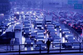 LOS ANGELES, CALIF. - MAR. 14, 2023. Traffic slows to a crawl on the rain-slicked Harbor Freeway in downtown Los Angeles as an atmospheric river pushes through Southern California on Tuesday, Mar. 14, 2023. (Luis Sinco / Los Angeles Times)