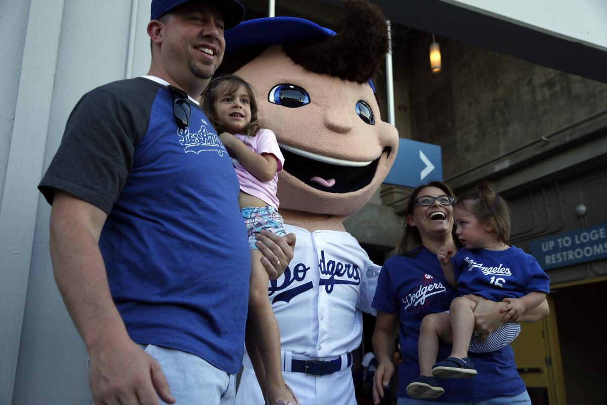 Jeff and Maria Nace along with children, Olivia, 3, left, and Bianca, 1, from Rancho Cucamonga pose for a photo with a Dodgers character as they arrive to the left field pavilion area at Dodger Stadium. The Dodgers aren't calling it a mascot though -- they prefer the term "performance character."