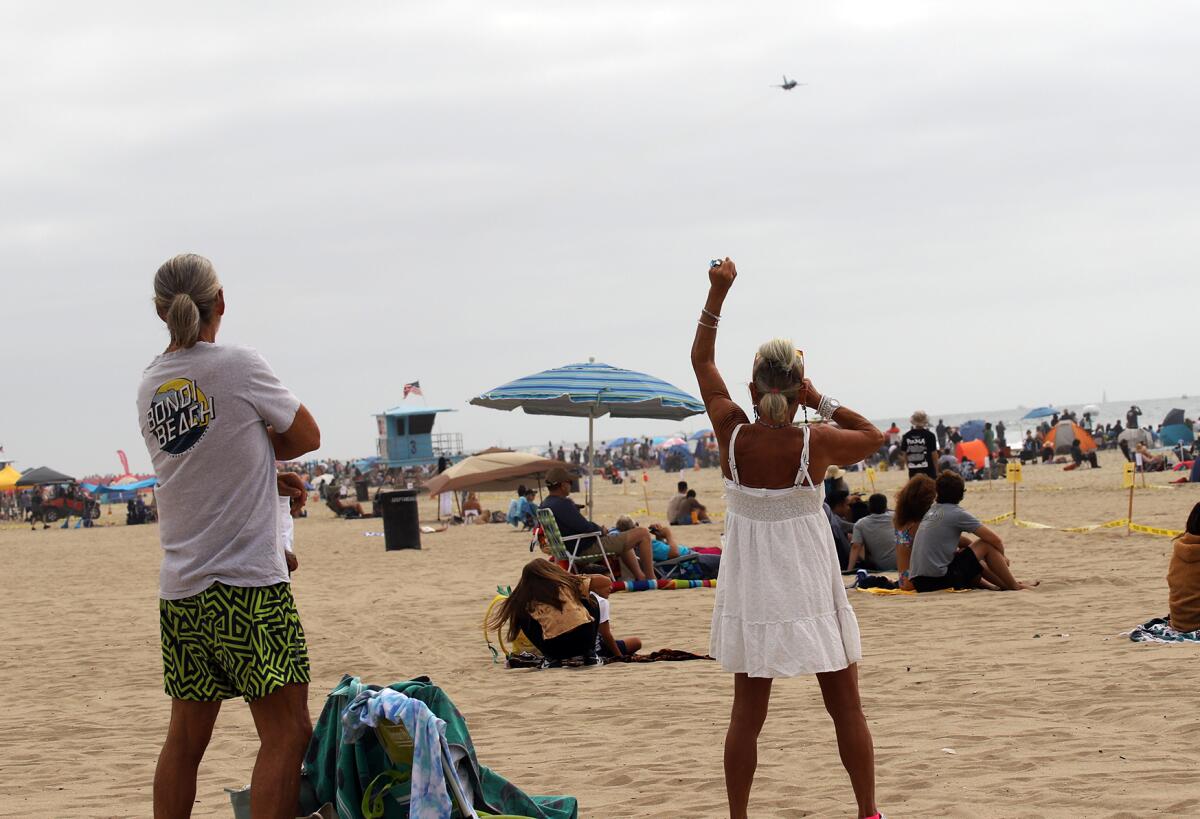 People cheer as U.S. Air Force pilots fly along  the Huntington Beach shoreline Friday during the Pacific Airshow.