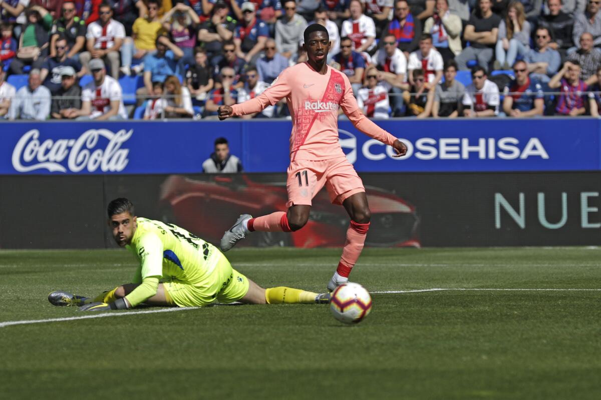 El delantero de Barcelona Ousmane Dembele, dispara a puerta con el portero de Huesca Roberto Santamaria en el suelo en un partid de La Liga el sábado, 13 de abril del 2019. (AP Foto/Manu Fernandez)