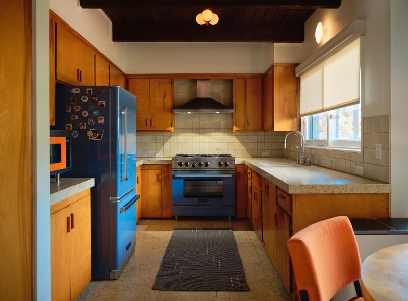 A mid-century modern style kitchen with blue and orange accents.