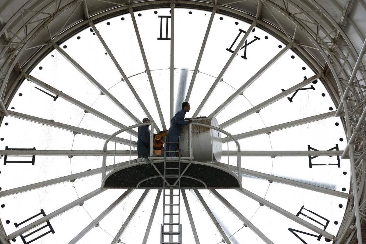 A worker climbs a ladder in the town of Cergy, France, to check on its huge clock. Daylight saving time ended Sunday in France.