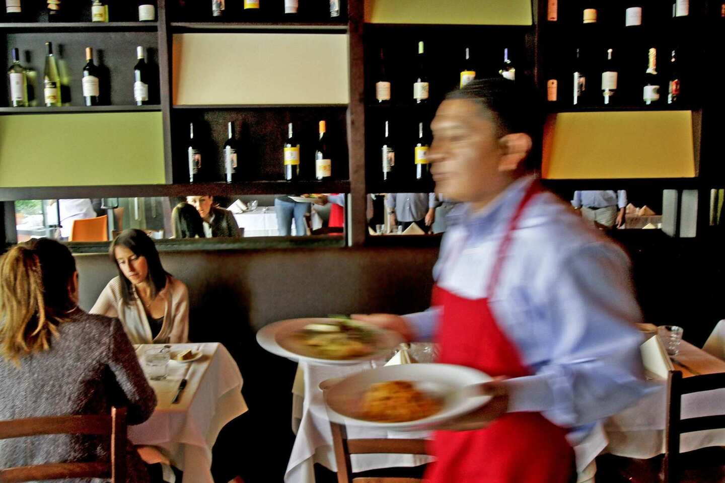 A waiter delivers meals in one of the dining rooms in the space that previously was Il Buco.