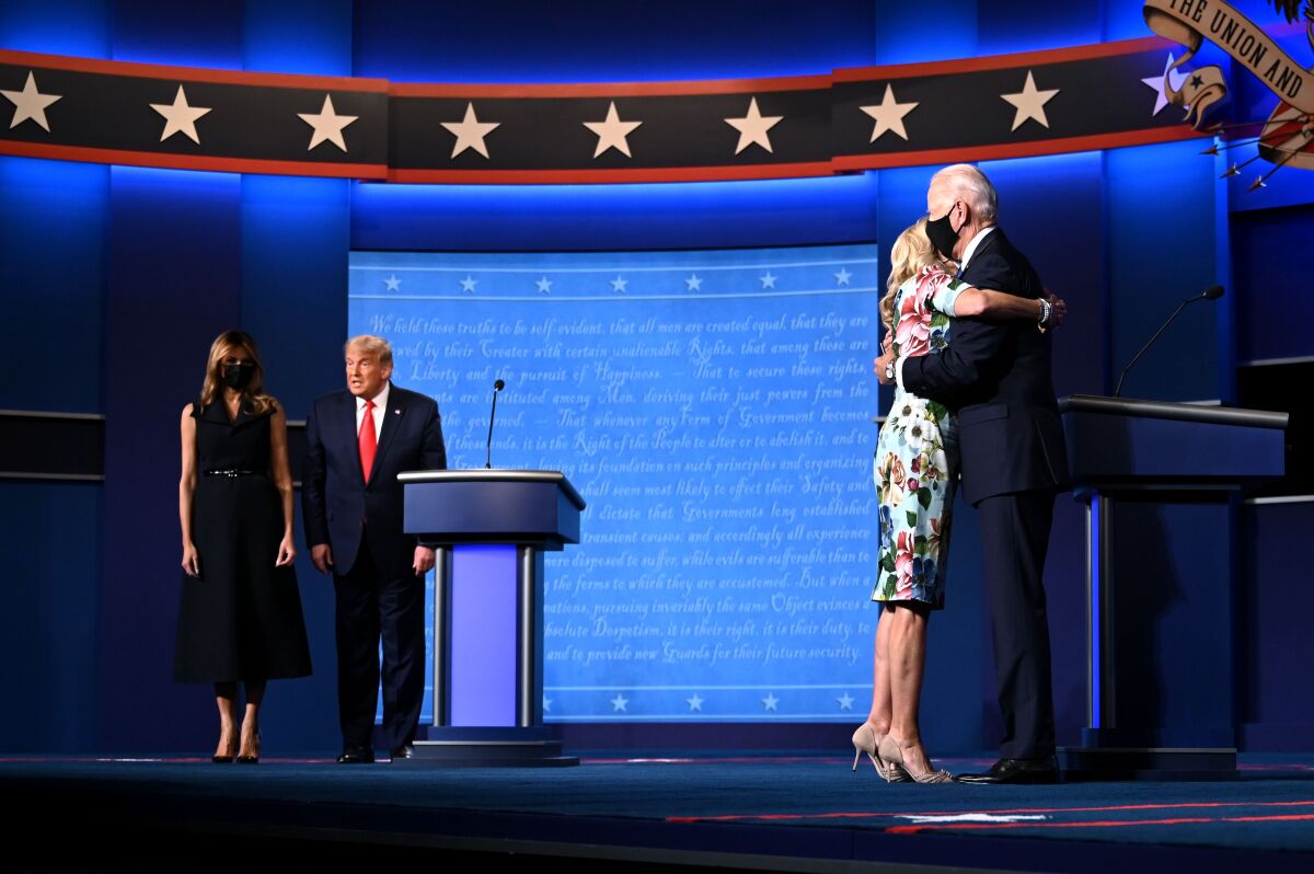 First Lady Melania Trump stands onstage by President Trump as Jill Biden hugs husband Joe Biden after the Nashville debate.