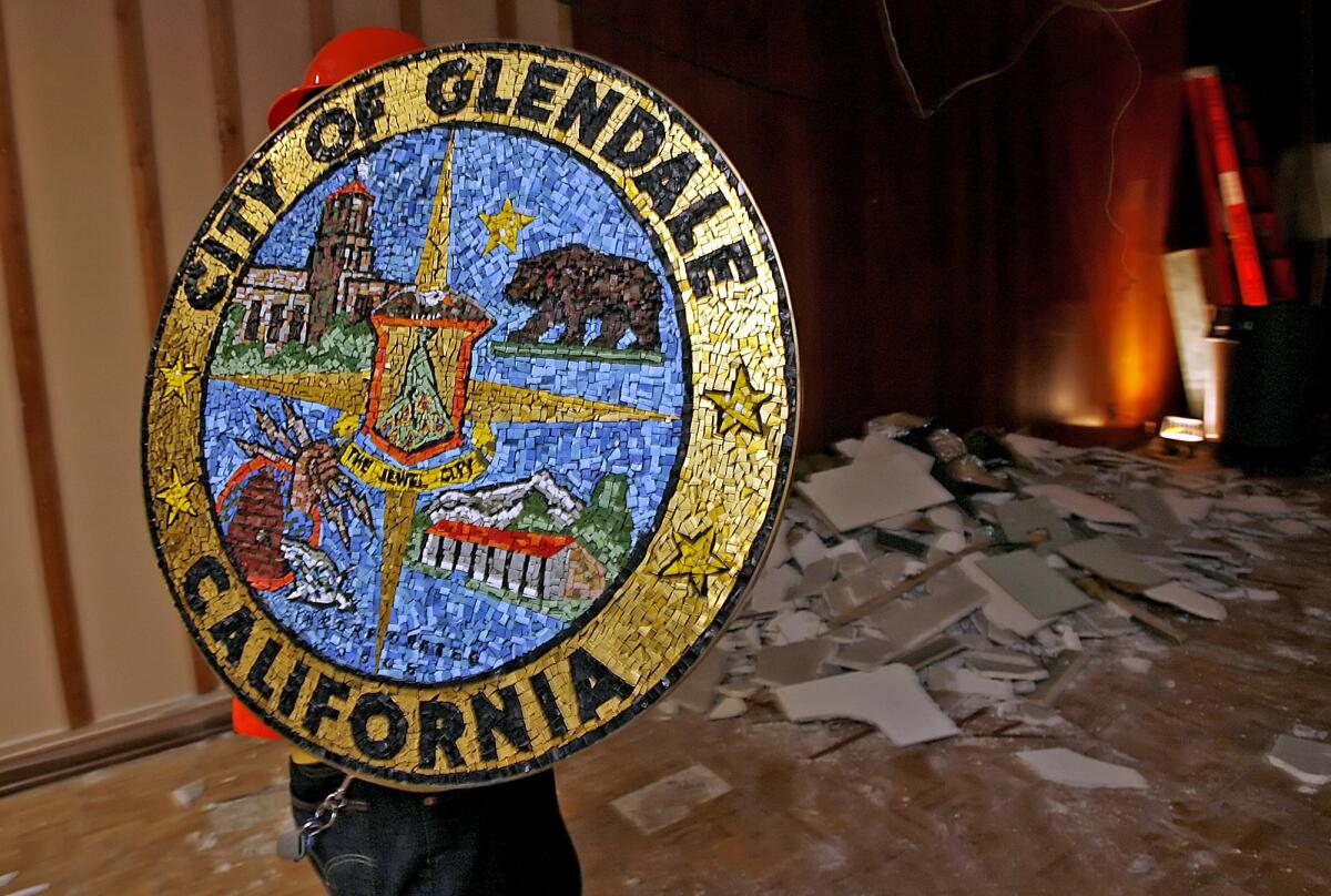 In this file photo from 2010, a city worker removes the Glendale city seal from the council chamber during a refurbishment project at City Hall.