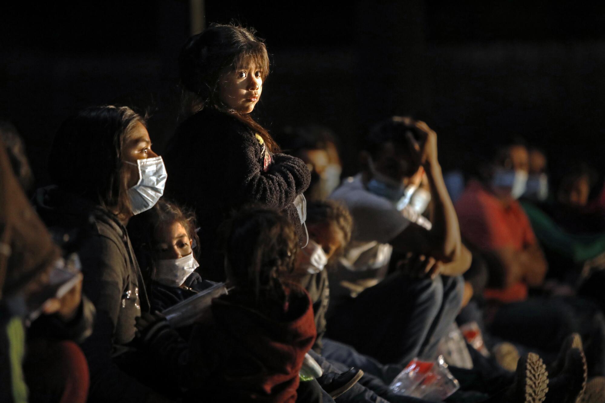 A young girl waits with her mother