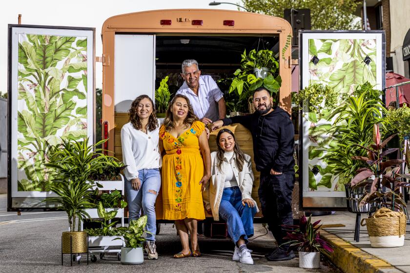 PASADENA, CALIFORNIA, March 19, 2022: (L to R) Wendy, Vilma, Cindy, Edwin Jr., and (top) Edwin Alvarado, family and owners of Pasadena Roots, a mobile plant store, pose for a portrait on Saturday March 19, 2022, in front of their small-trailer plant shop,which they named La Chula (Cutie), at the day's pop-up location in front of CAR Artisan Chocolate - Manufactory & Cafe in Pasadena, Cali. The family started the plant shop from their home during the Covid-19 pandemic lockdown in the Summer of 2020, and have since developed it into a pop-up and mobile store in a small trailer, which they've named La Chula (Cutie). (Silvia Razgova / For the Times)