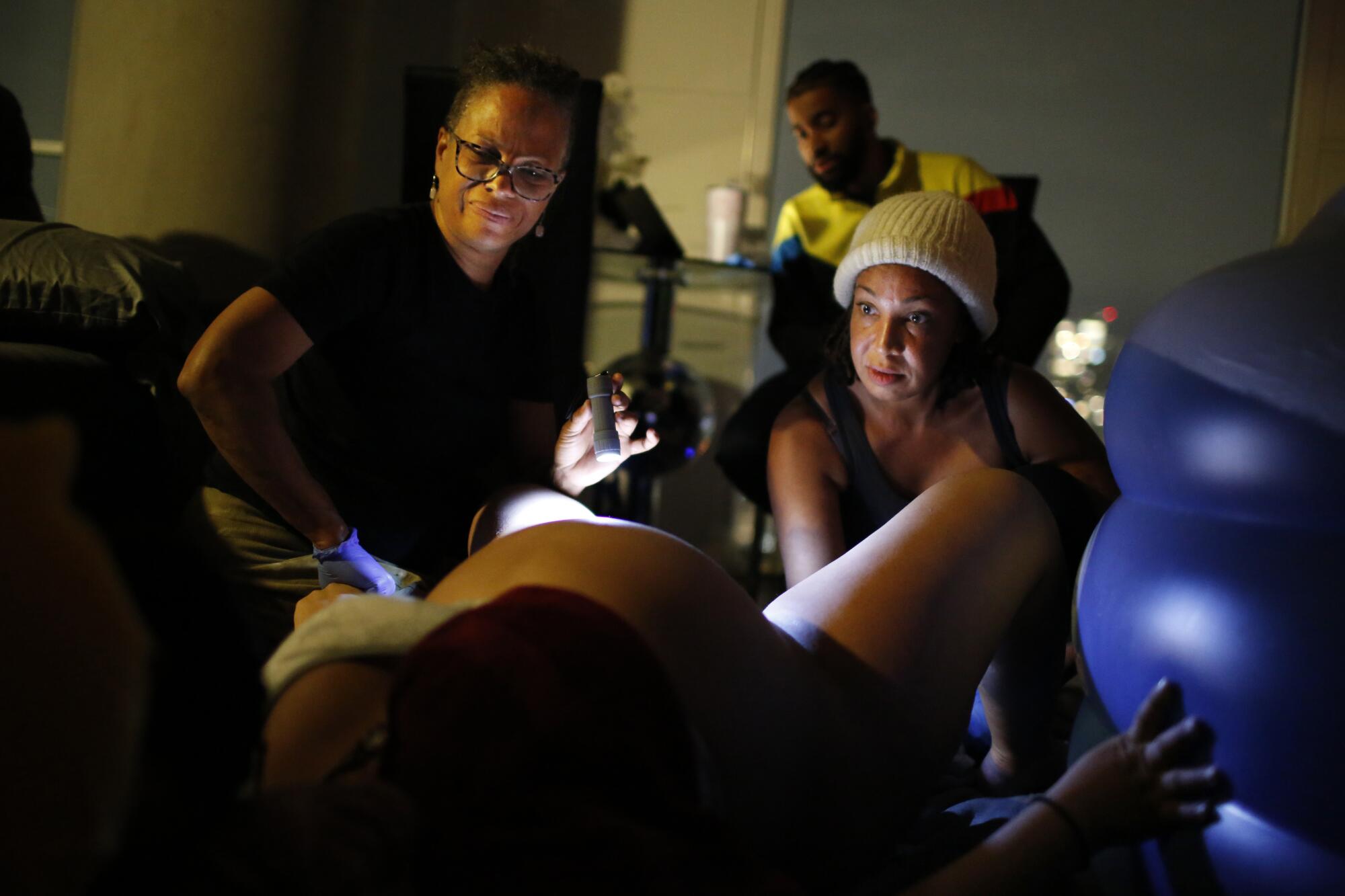 Two women assist a woman during labor