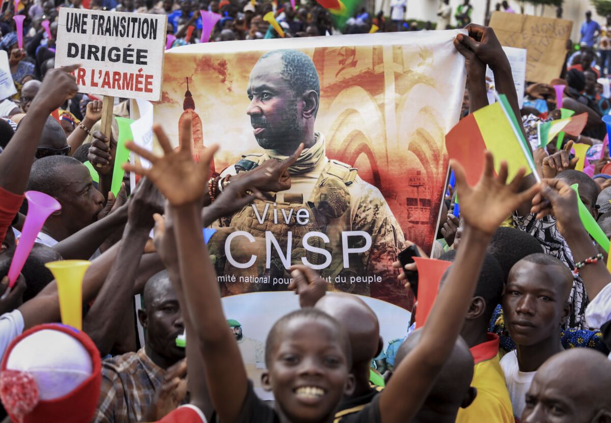 People hold a banner showing Col. Assimi Goita, leader of the junta which is now running Mali and calls itself the National Committee for the Salvation of the People, as they demonstrate to show support for the junta in the capital Bamako, Mali, Tuesday, Sept. 8, 2020. Placard at left in French reads "An army-led transition". (AP Photo)