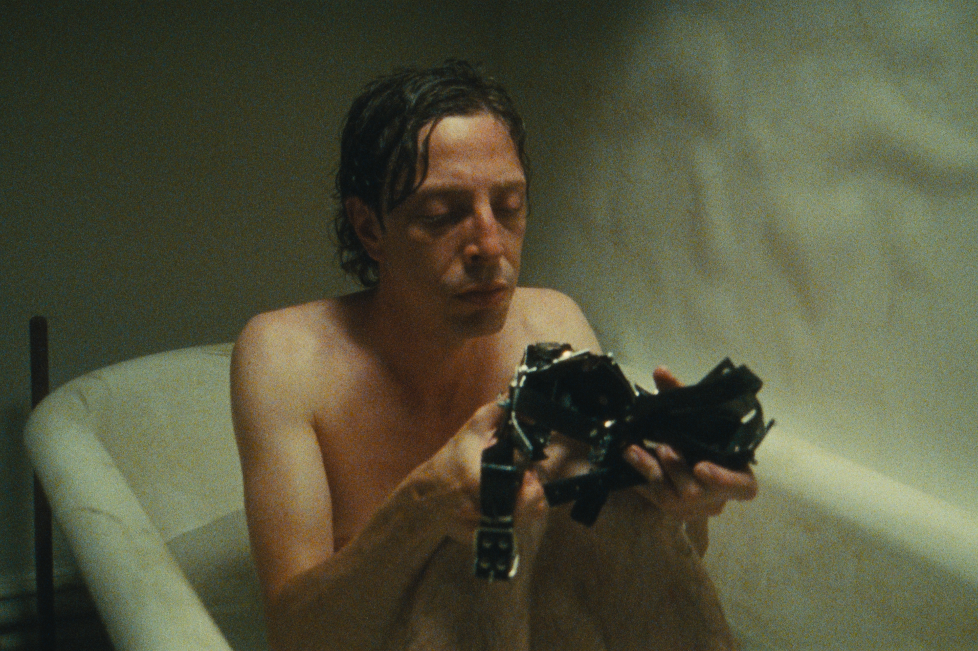 A sad man sits in a bathtub.
