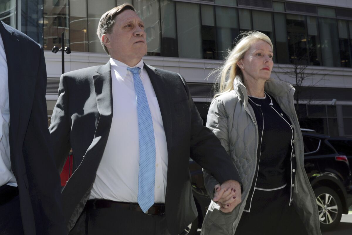 A man arrives at federal court, with his wife holding his hand