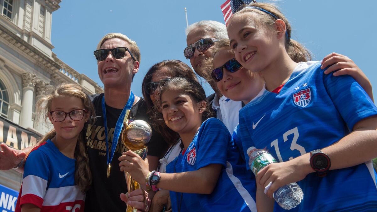 U.S. captain Abby Wambach shares the Women's World Cup trophy with fans as New York Mayor Bill de Blasio during a team championship celebration in New York on Friday.