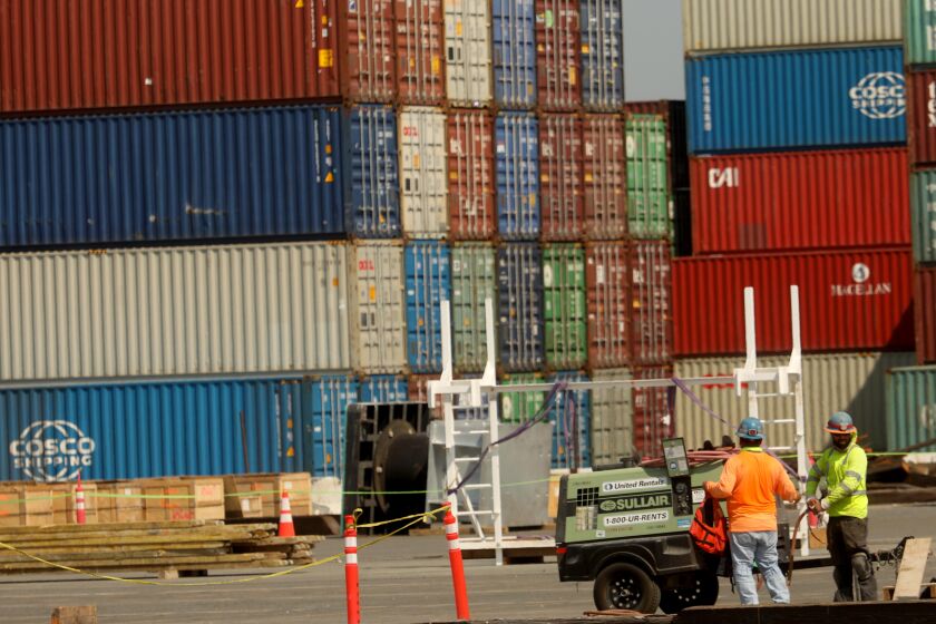 WILMINGTON, CA - AUGUST 27, 2020 - - Men work against a backdrop of shipping containers at the Port of Los Angeles, where California air quality officials are poised to adopt pollution-cutting regulations, targeting diesel trucks and cargo ships. (Genaro Molina/Los Angeles Times)