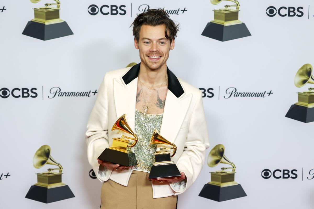 A man holds his two Grammy awards backstage