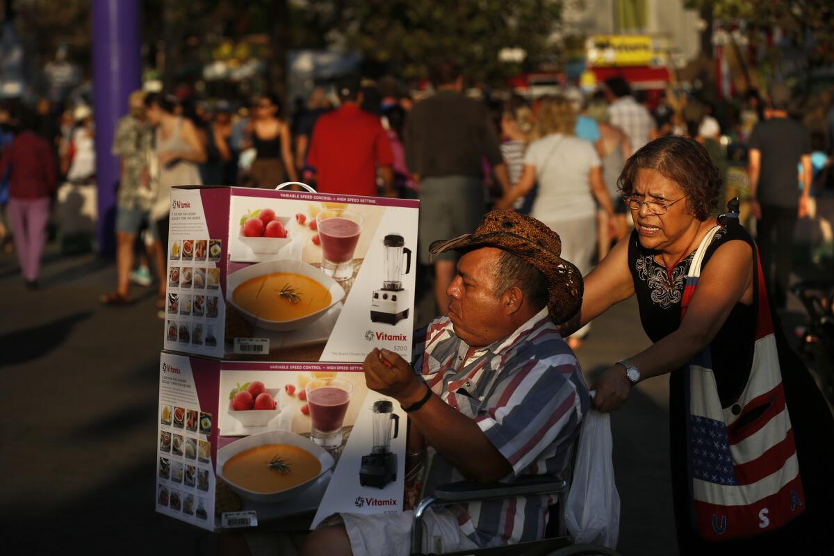 Jorge Iturbe, of Ontario, and his sister Elodia Castro, of Fontana, walk through the Los Angeles County fair in Pomona where they had just purchased two new Vitamix machines. ( Rick Loomis / Los Angeles Times )