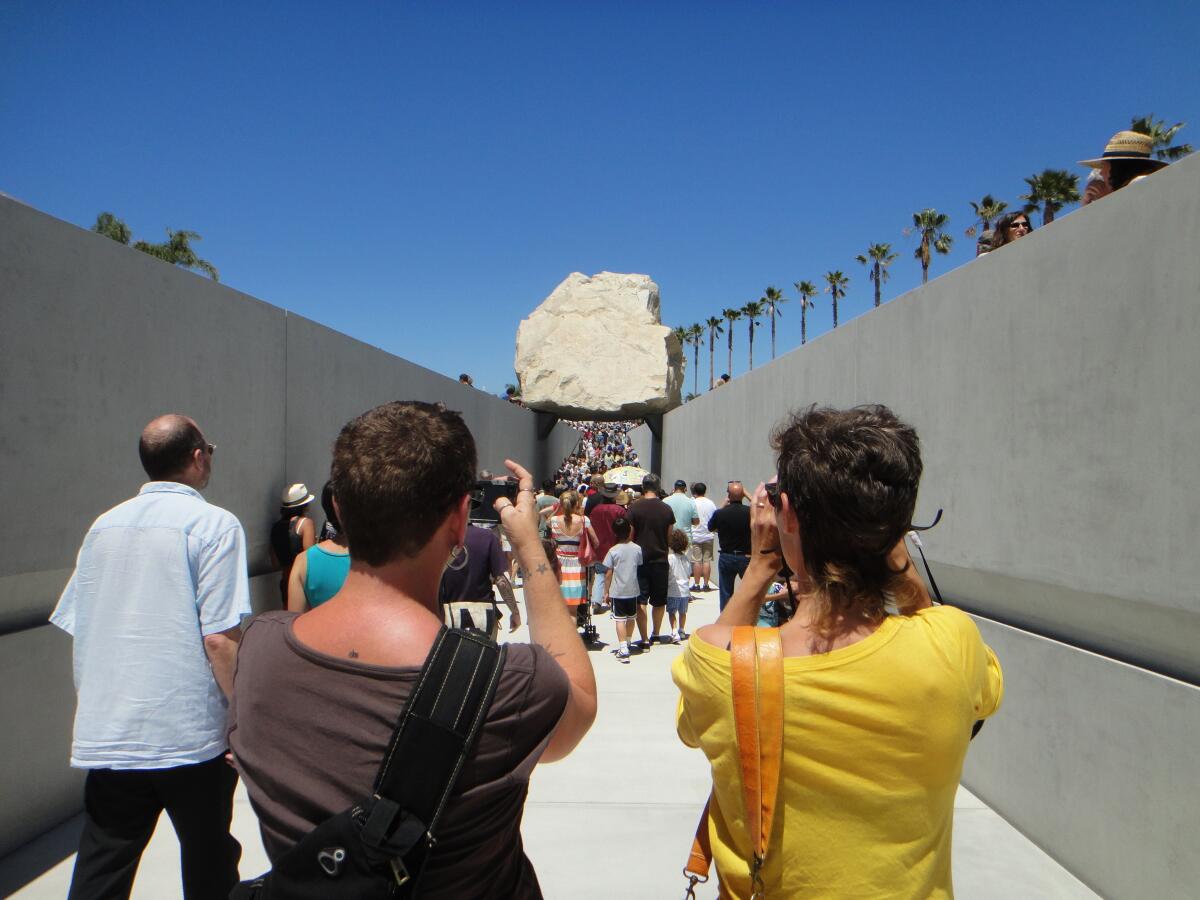 A pair of onlookers photograph Michael Heizer's "Levitated Mass" boulder sculpture at LACMA 