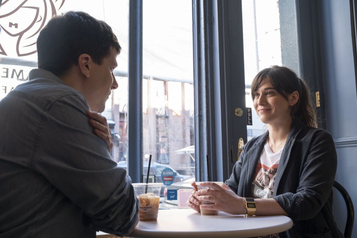 Jesse Eisenberg and Lizzy Caplan sit at a coffeehouse table in a scene from "Fleishman Is in Trouble." 