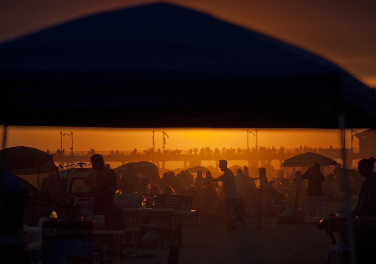 Independence Day revelers bask in the setting sunlight before watching fireworks shoot off the Huntington Beach pier on July 4, 2013.