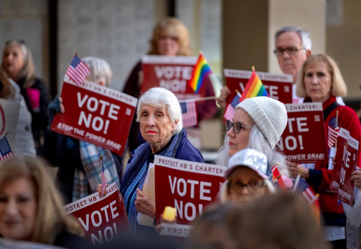 A group of people hold signs that say 'Vote No' outside a building.