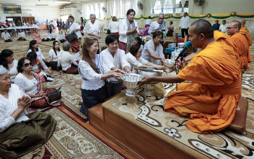 Worshipers make their offerings to monks at Khemara Buddhikarama
