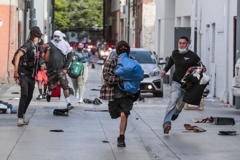 Santa Monica, CA, Sunday May 31, 2020 - Looters rush away from police after picking through a store downtown plunder stores as protestors face off with police as unrest continues in the wake of the death of George Floyd in Minneapolis. (Robert Gauthier / Los Angeles Times)