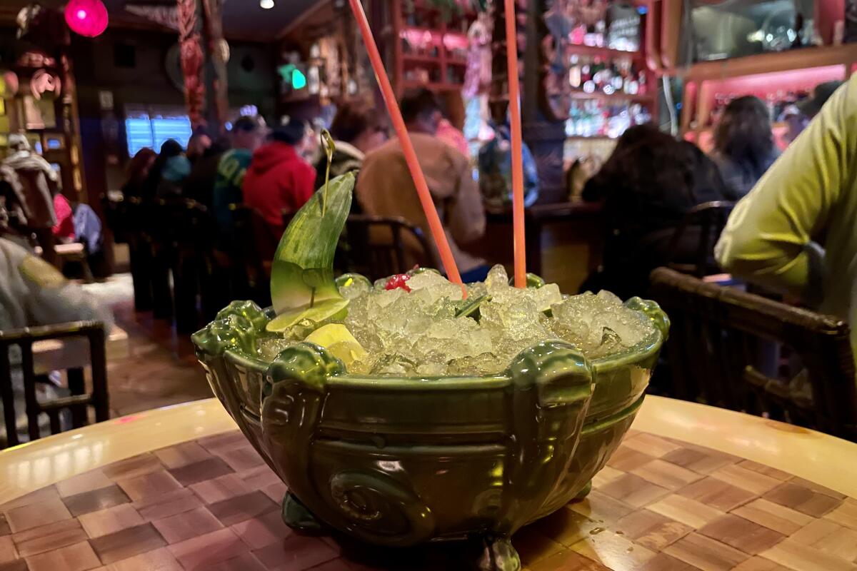 A large ceramic bowl with several long straws protruding from the icy drink it contains