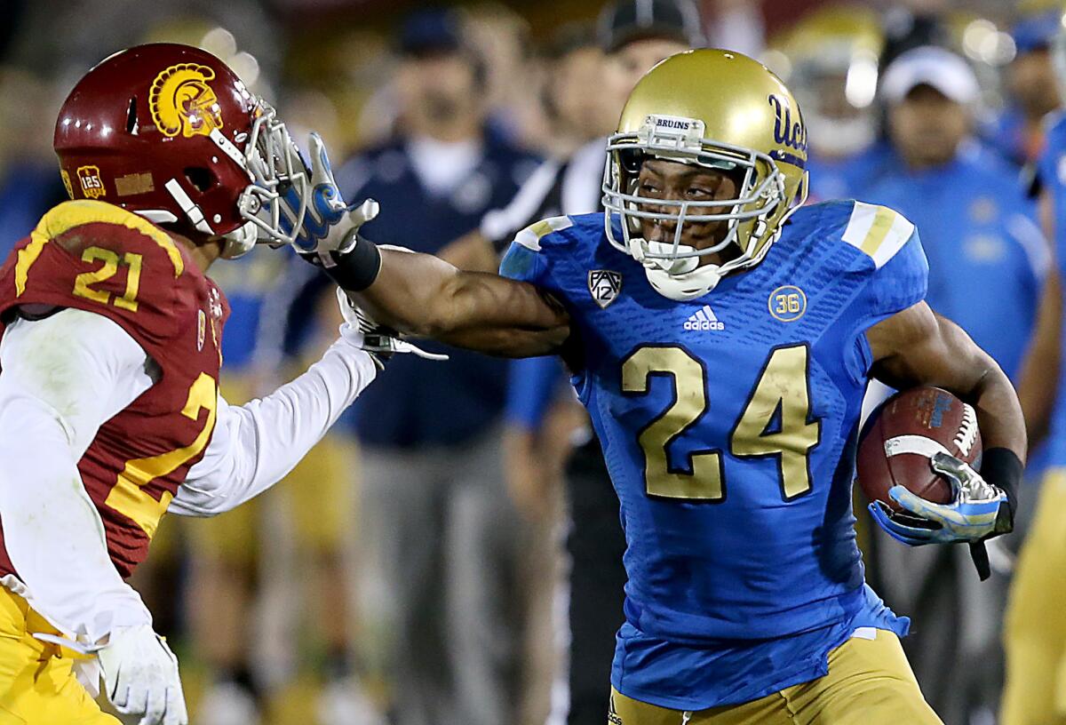 USC safety Su'a Cravens (21) fends off a stiff-arm move by Bruins running back Paul Perkins to make a tackle after a reception during last season's rivalry game.