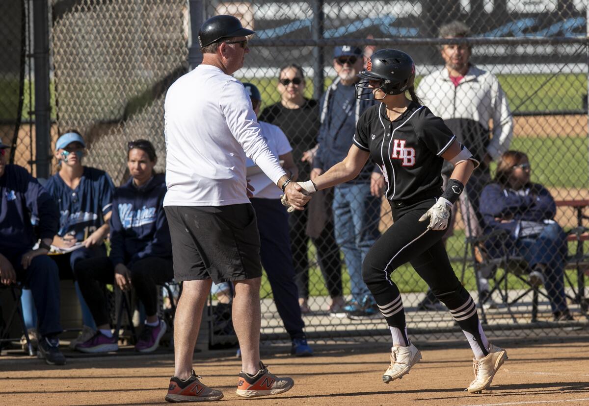 Huntington Beach coach Jeff Forsberg high-fives Zoe Prystajko after hitting a home run in the fourth inning.