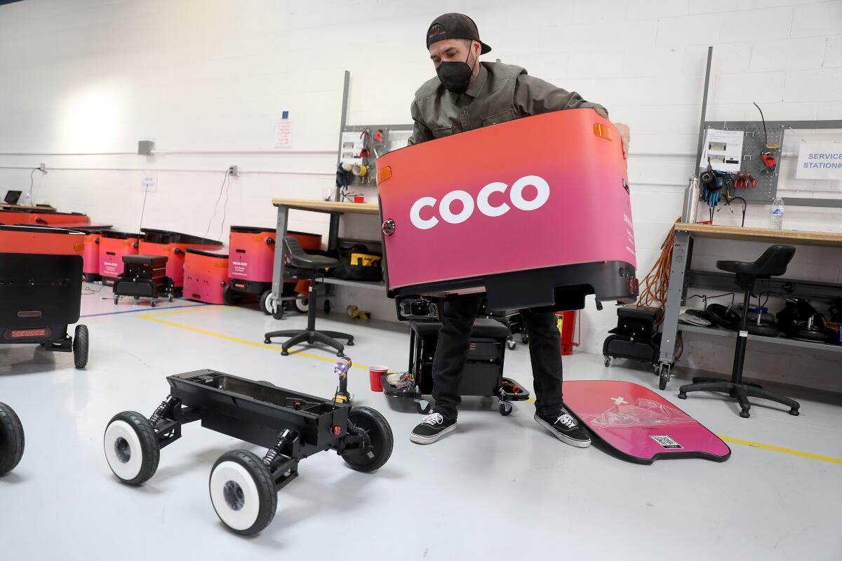 Grant Rodriguez assembles a robot at a Coco facility.