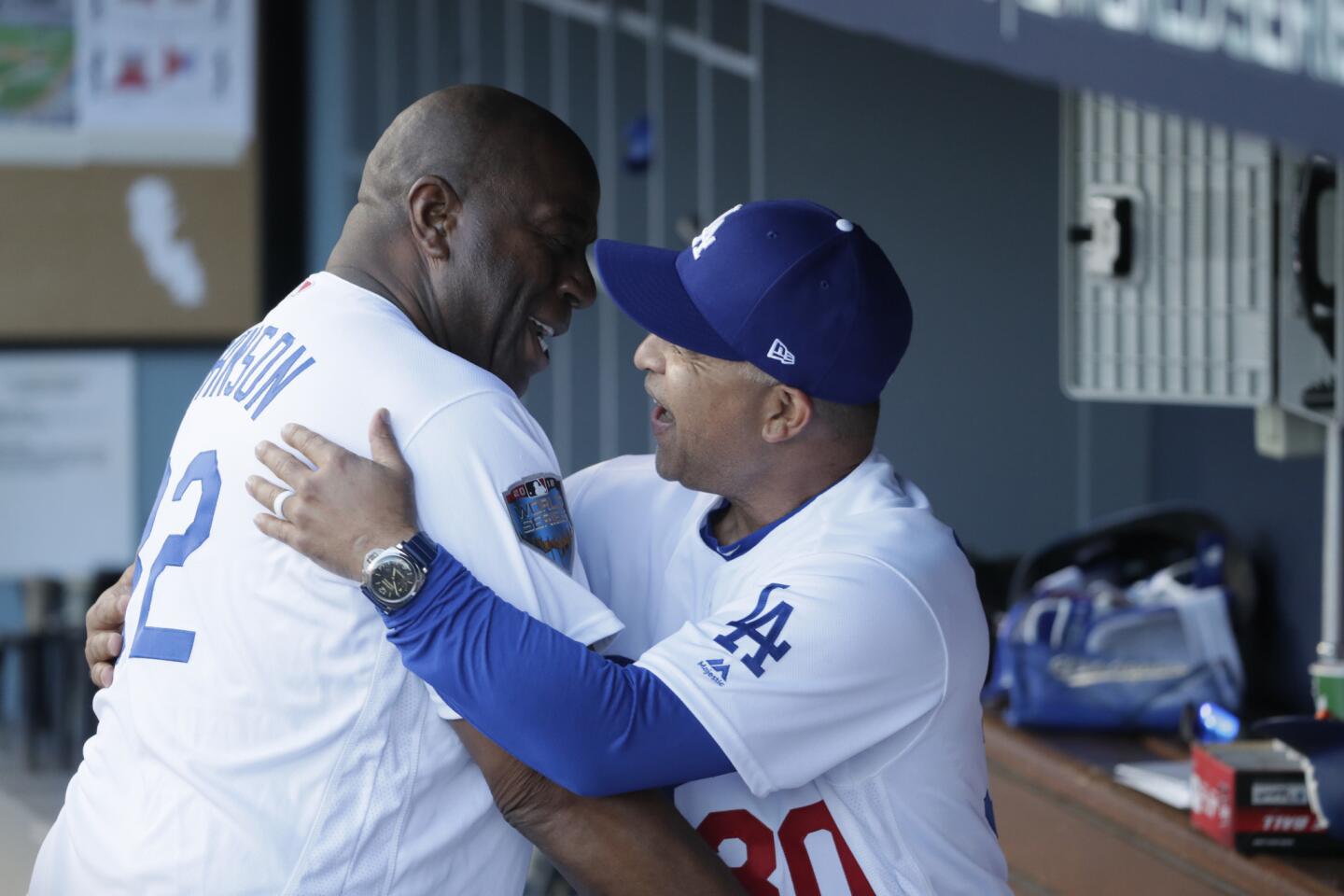 Magic Johnson hugs Dodger manager Dave Roberts before the start of Game 3 of the World Series at Dodger Stadium.